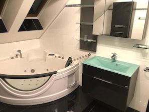 Une salle de bain moderne avec une baignoire îlot, un lavabo doté d’un plan de toilette de couleur turquoise et un meuble-lavabo noir.