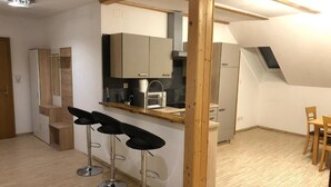 A modern kitchen with wooden accents, a dining area with a table and chairs, and a bar area with stools. - Pension Günther (Graz)