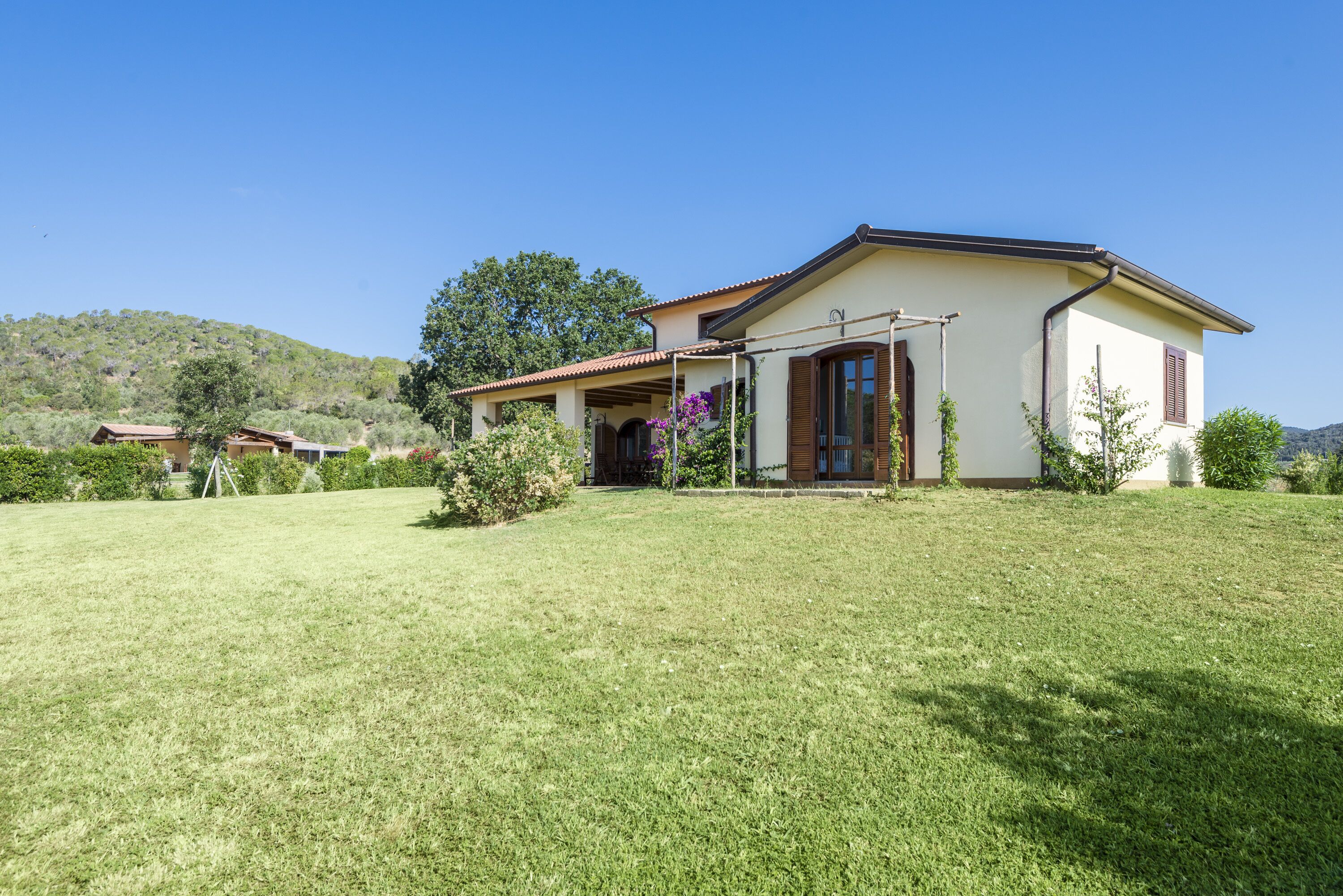 A single-story house with a flat roof, a covered porch, and a well-maintained lawn.