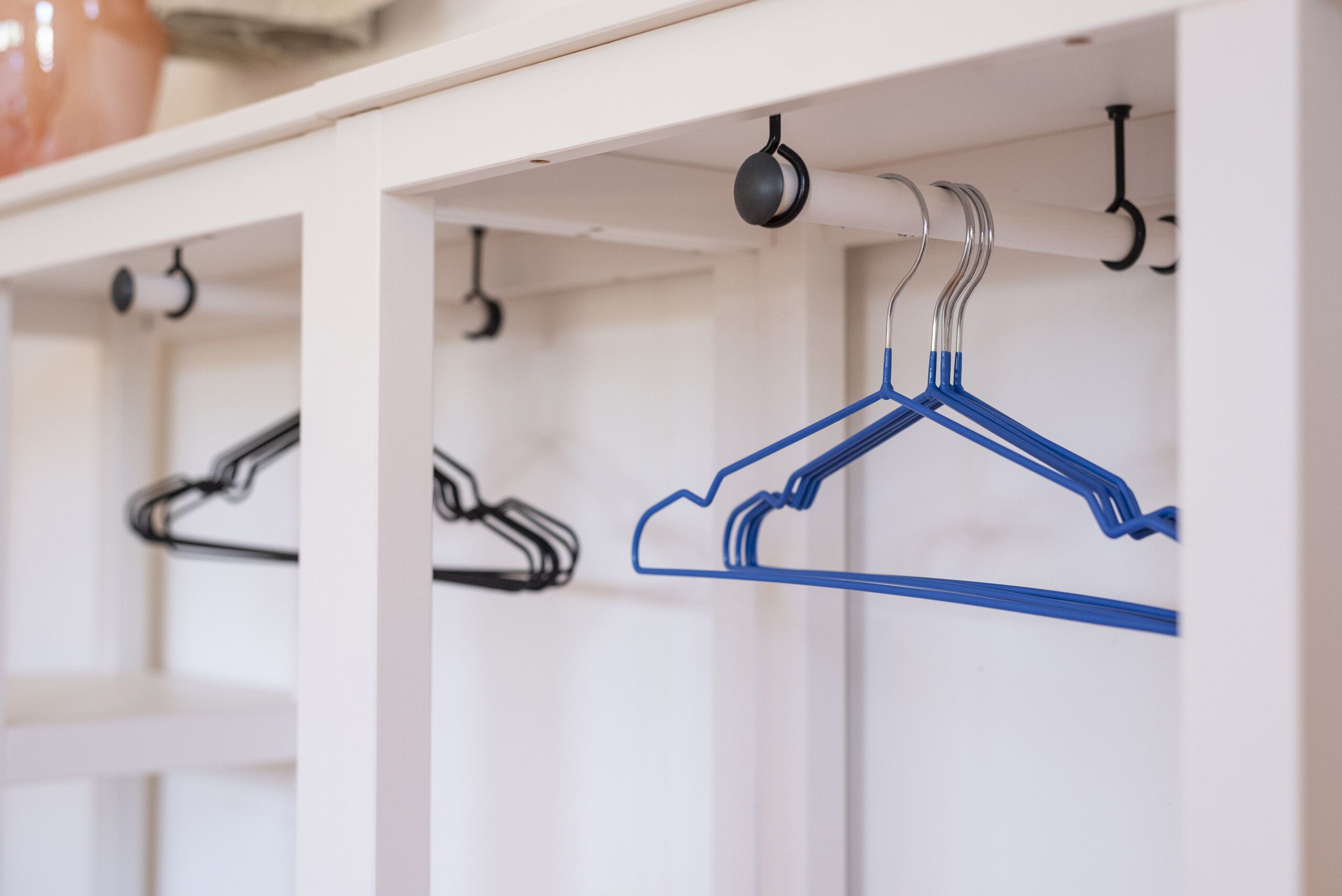 A row of white shelves with metal hangers and a blue hanger.