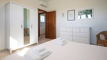 Een slaapkamer met een bed, een kledingkast, een dressoir en twee foto's in lijsten aan de muur.