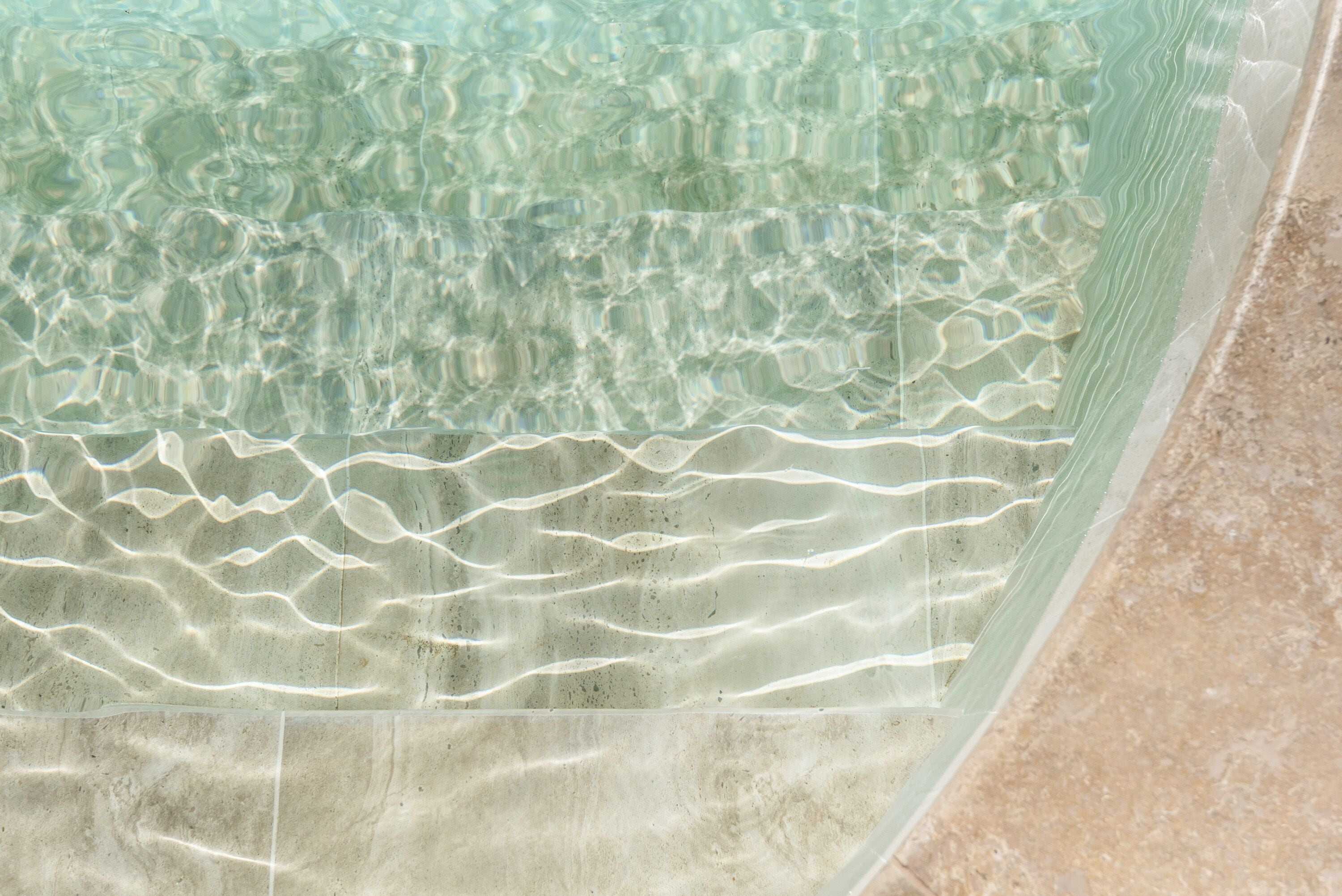 On voit clairement une piscine, avec des ondulations à la surface de l'eau et un bord carrelé.