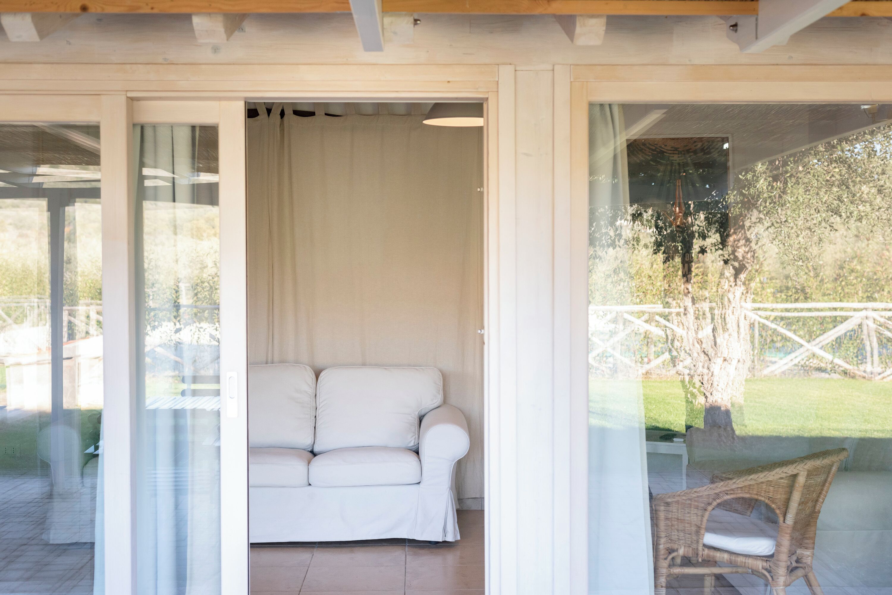 Un sofá blanco en una habitación con un ventanal que da a un patio.