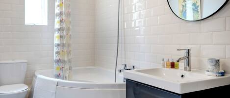 A bathroom with a bathtub, toilet, sink, and a mirror with a book.