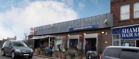 A building labeled "Queen's Park Station" with a "Sham Hair Salon" across the street.