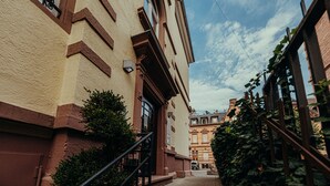 Un estrecho callejón flanqueado por edificios, una escalera y un cielo despejado.
