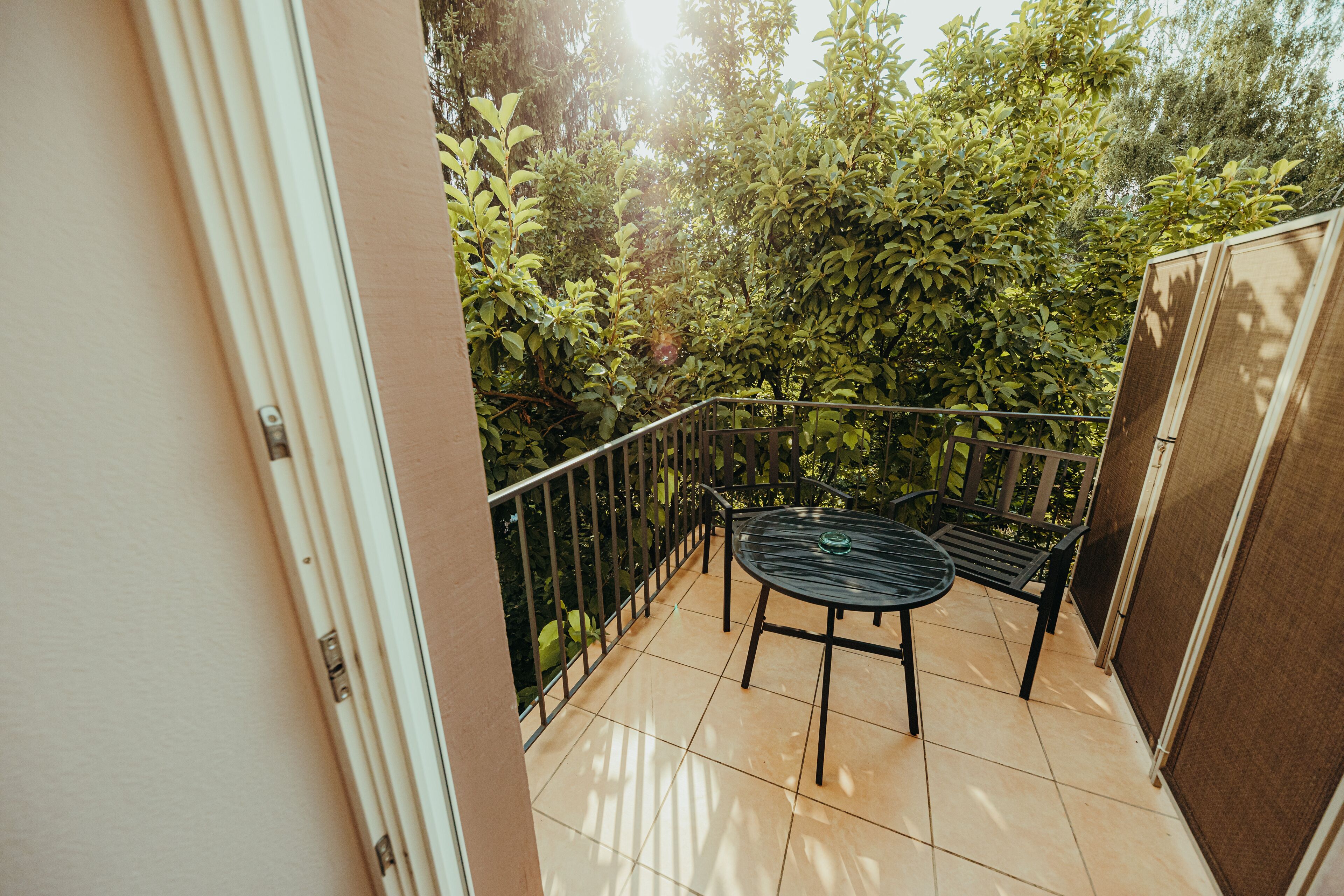A balcony with a table and chairs, surrounded by dense foliage.
