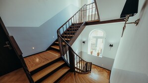 Una escalera de madera con barandal negro que conduce a una plataforma con ventana.