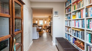 A hallway with a wooden cabinet, a bookshelf filled with books, and a bench. - A Hidden Mews (London)