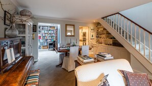 A cozy living room with a piano, a bookshelf, and a staircase. - A Hidden Mews (London)