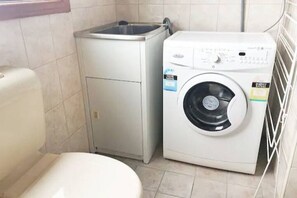 Compact laundry room with a washing machine and toilet, offering a convenient space for laundry and bathroom needs.