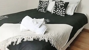 A neatly made bed with a black and white patterned bedspread, white pillows, and a white towel. - Secret Dream Location with WIFI and Wine (Rye)