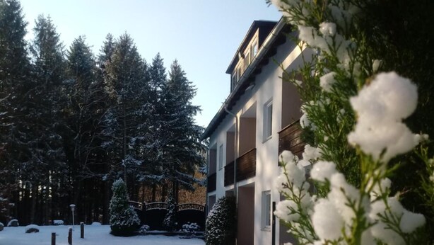 A snow-covered courtyard with a building featuring balconies and a sign that reads "Hotel". - Falkenhof (Westensee)