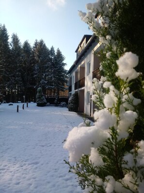 A snow-covered courtyard with a building featuring balconies and a sign that reads "Hotel". - Falkenhof (Westensee)