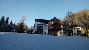 A multi-story residential building with a flat roof and a balcony on the second floor. - Falkenhof (Westensee)