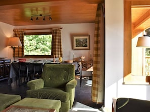 A cozy room with a dining table, chairs, a green armchair, and a window with curtains. - Apartment near slopes, pets welcome - 8 guests (Méribel)