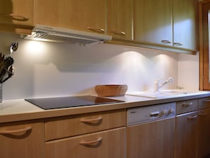 A kitchen with wooden cabinets, a built-in stove, a sink, and a dishwasher. - Apartment near slopes, pets welcome - 8 guests (Méribel)