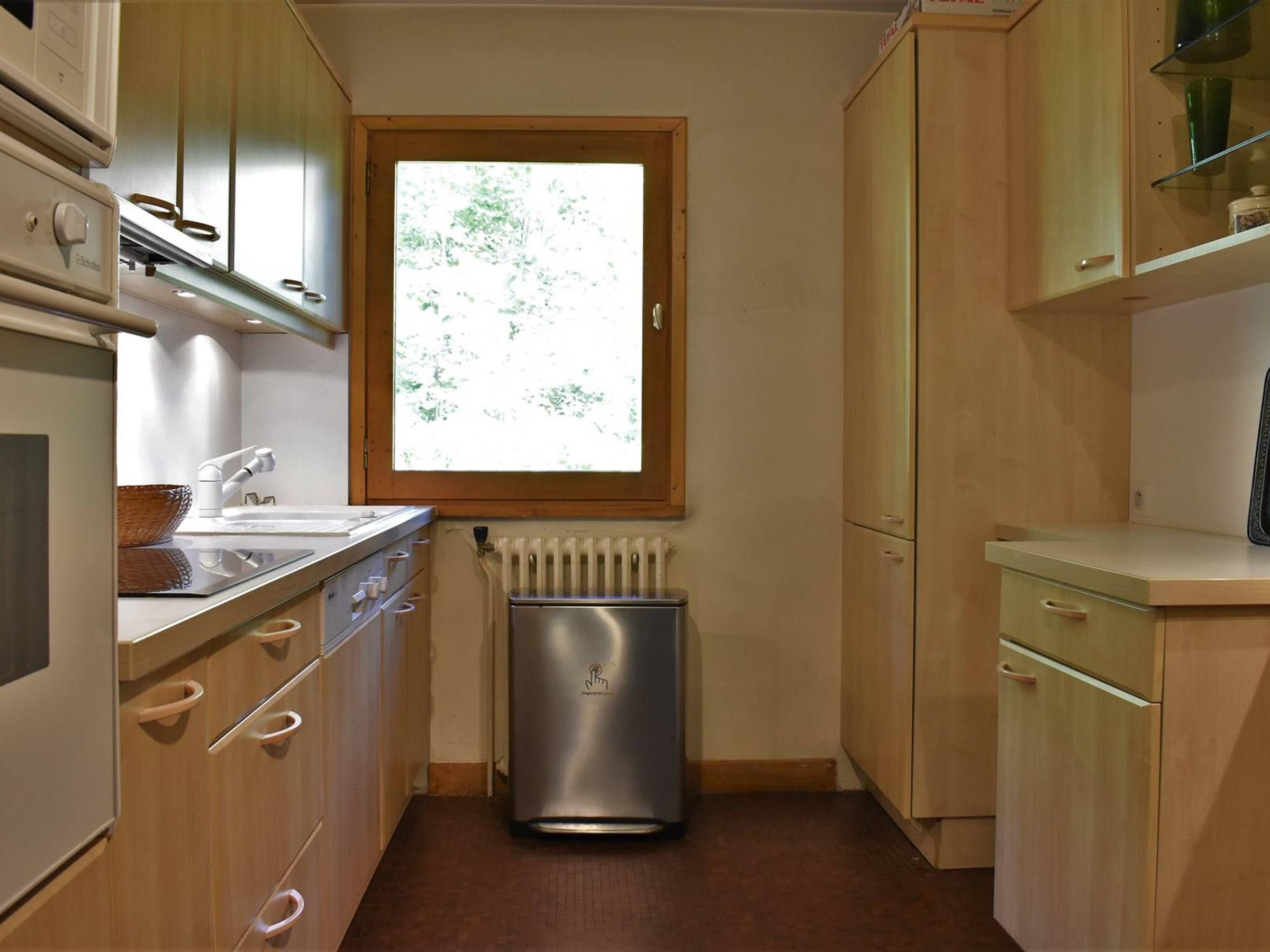 Una cocina compacta con ventana, un radiador y armarios de madera.