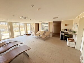 Ein geräumiges Zimmer mit großem Fenster, einer Essecke und einer Sitzecke mit Stühlen.