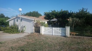 Een huis met een witte picket fence, een tuin en een helderblauwe lucht.