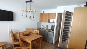 Een kleine keuken met houten kastjes, een inbouwmagnetron en een spoelbak.
