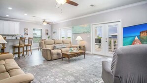 Un salon spacieux avec un canapé beige, une table basse en bois et un ventilateur de plafond.