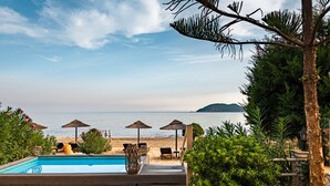 Un espace piscine avec vue sur la mer, agrémenté de chaises longues et de parasols.
