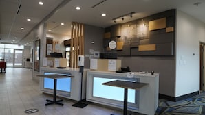 A reception area with two reception desks, a large window, and a wall-mounted information board. - Holiday Inn Express & Suites Dallas Central Market Center by IHG (Dallas)