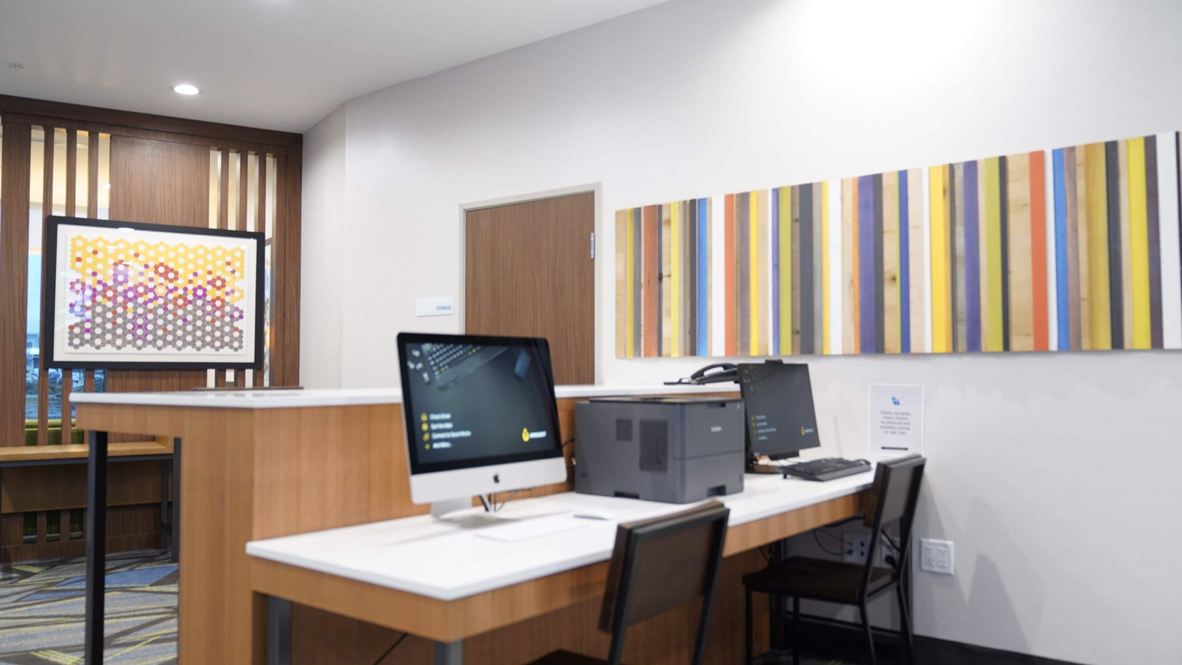 A modern office space with a desk, computer, and a large abstract painting on the wall.