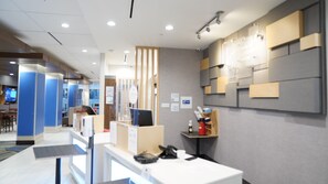Eine moderne Hotelhalle mit Empfangsschalter, Sitzgelegenheiten und einer großen Wand mit Stauraumeinheiten.