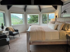 A bedroom with a large bed, multiple windows, a desk, and a chair. - Luxurious Mt CB Home | 6 Bedroom | Best Views in CB | Hot Tub | Gas Grill (Mt. Crested Butte)