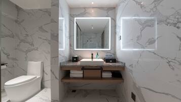 Un baño moderno con suelo de mármol, inodoro blanco, lavabo con espejo y un perchero para toallas.