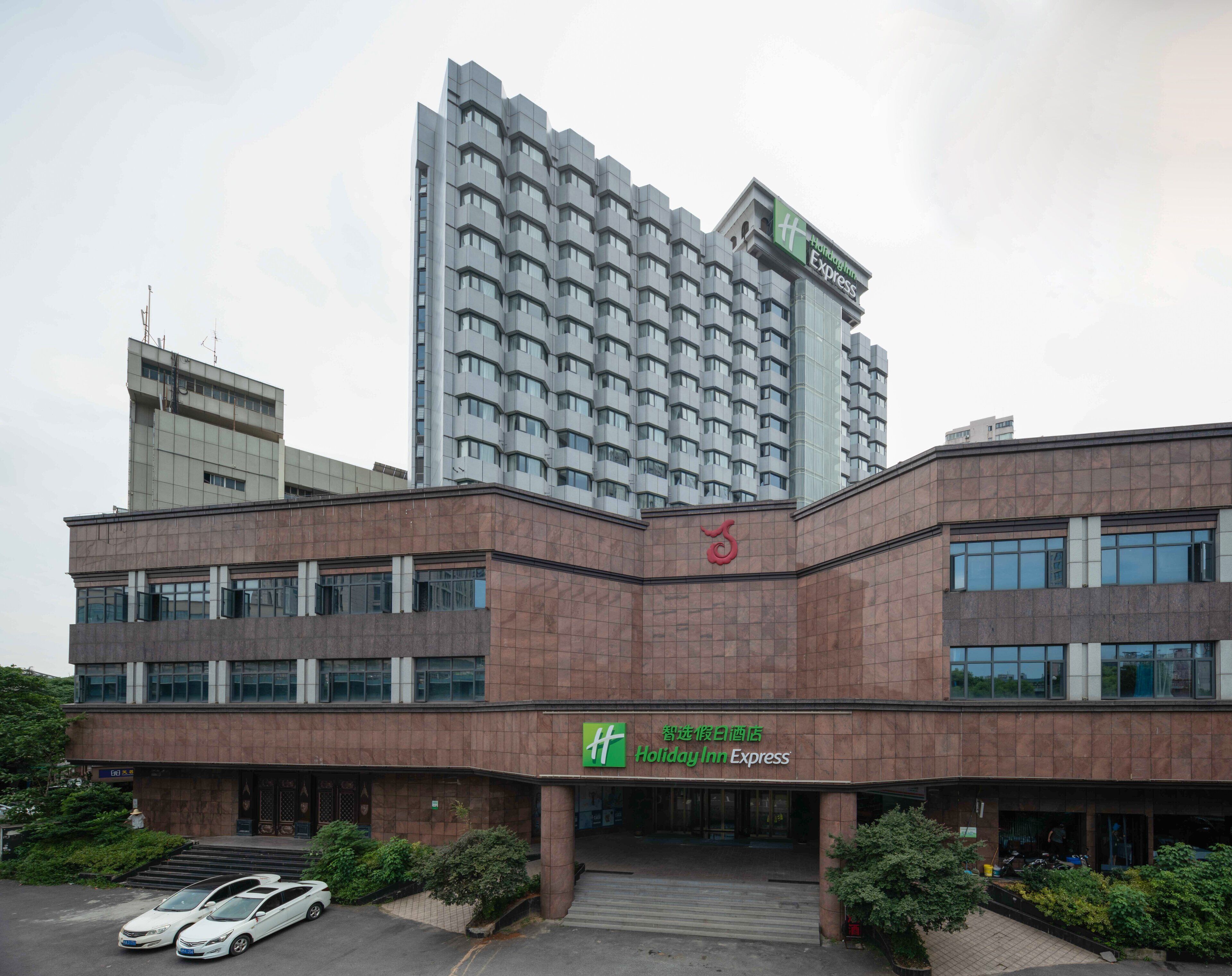 Een Holiday Inn Express gebouw met een modern ontwerp, herkenbaar aan een opvallend logo en een ruime entree.