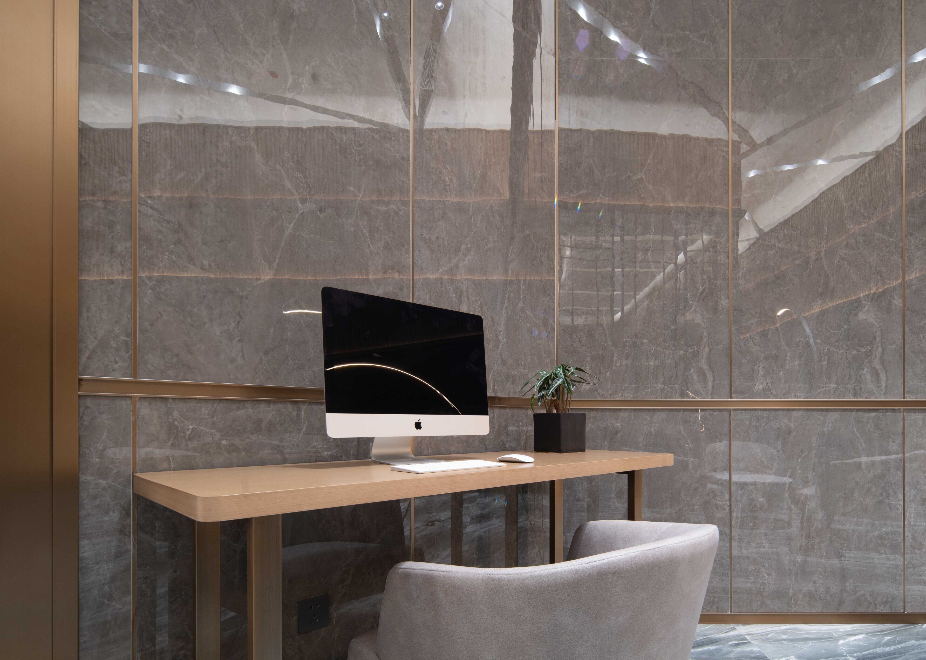 A modern office space with a wooden desk, a computer monitor, and a plant.