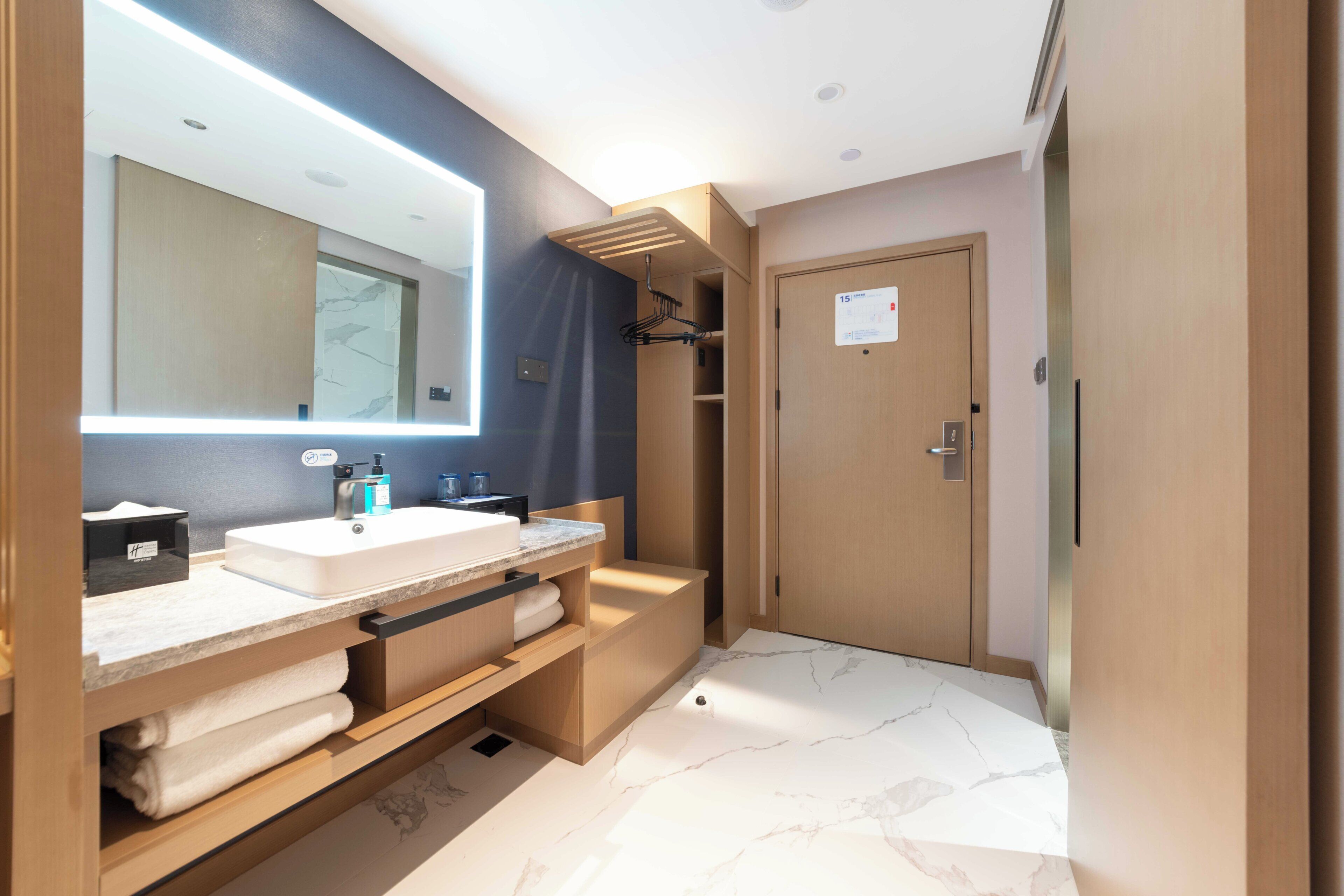 A modern bathroom with a double sink, a large mirror, and a towel rack.