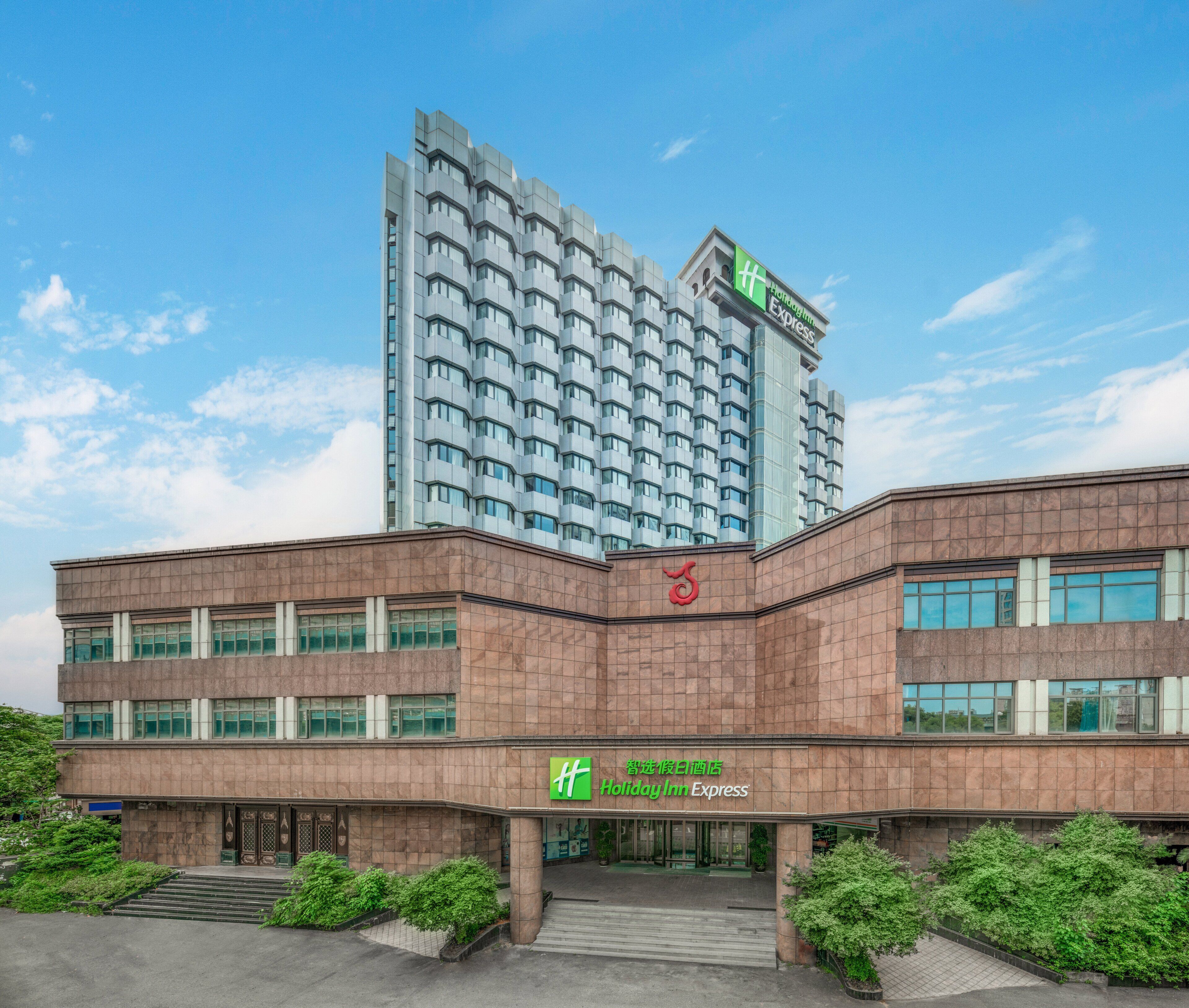 Un hotel Holiday Inn Express dal design moderno, con una torre imponente e un edificio a due piani con un'ampia entrata.