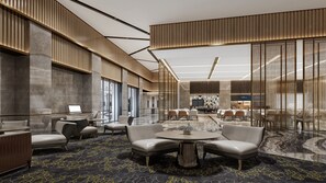 Een moderne hotellobby met een zithoek, een receptiebalie en een eetgedeelte.
