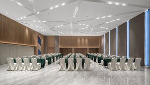 A conference room with rows of tables and chairs, a high ceiling with recessed lighting, and large windows on one side. - Holiday Inn Express Nanchang Bayi Square by IHG (Nanchang)