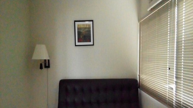 Et hotelværelse med en seng, et natbord, en lampe og et vindue med rullegardiner.