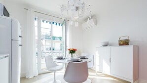Eine moderne Küche mit Essbereich, weißen Schränken und Blick auf die Stadt durch große Fenster.