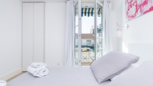 Ein Hotelzimmer mit Bett, Blick ins Freie und einem Balkon mit Tisch und Stühlen.