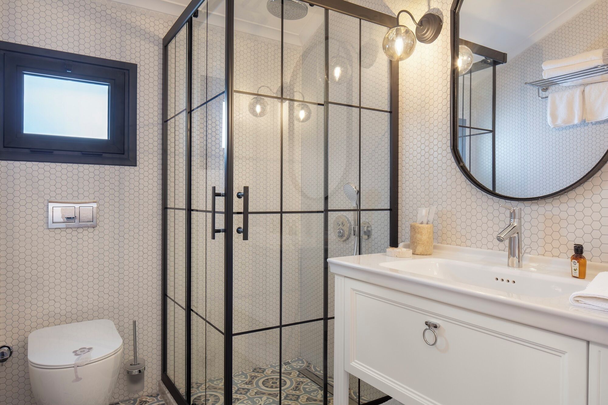 A modern bathroom with a glass-enclosed shower, a white vanity with a mirror, and a toilet.