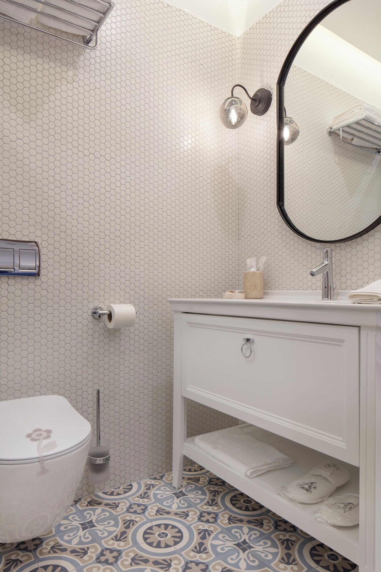 A bathroom with a toilet, a sink with a mirror, and a towel rack.