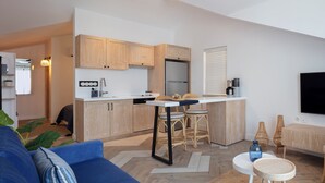 Un espace de vie compact comprenant un coin cuisine, un coin repas et un coin salon avec un téléviseur.