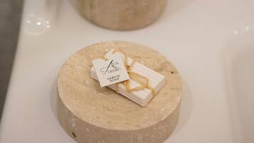 Un bagno con un portasapone beige che contiene una saponetta e un contenitore con bustine di sapone.