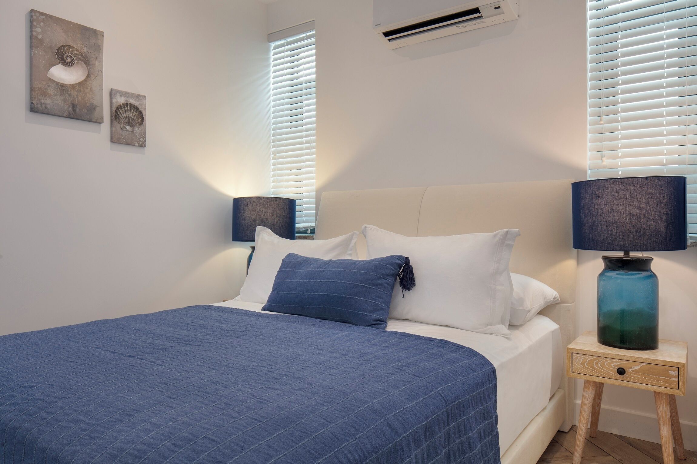 Un dormitorio con una cama, dos lámparas de pared y una mesita de noche con lámpara.