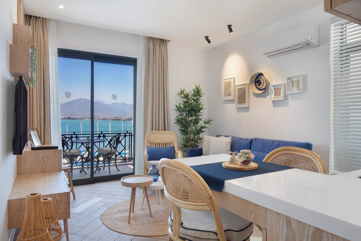A modern living room with a balcony, a dining area, and a view of the sea.