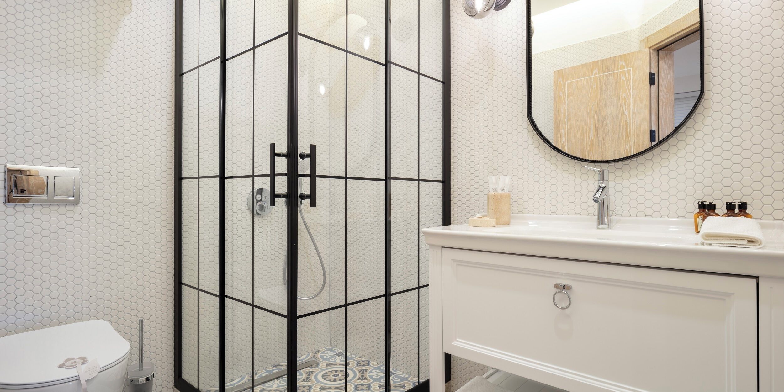 Un baño moderno con ducha envuelta en vidrio, inodoro blanco y tocador con espejo.