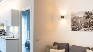 Una sala de estar moderna con un sofá, una lámpara de pared y un cuadro.