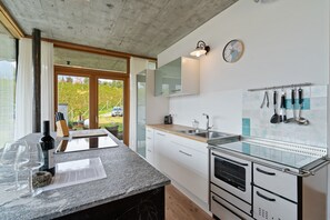 A modern kitchen with a granite countertop, stainless steel appliances, and a large window with a view of greenery.